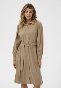 Beige corduroy dress with a collared neckline, long puff sleeves, a belted waist, and button front closure, featuring vertical ribbed texture.