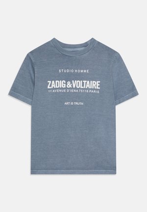 Niebieska koszulka z krótkim rękawem i okrągłym dekoltem, z białym napisem: "STUDIO HOMME," "ZADIG & VOLTAIRE," "11 AVENUE D'IENA 75116 PARIS," oraz "ART IS TRUTH."