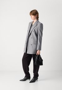 Grijze double-breasted blazer, zwarte hoge taille broek, spitse zwarte laarzen, kleine zwarte handtas, gladde texturen, gestructureerde pasvorm.