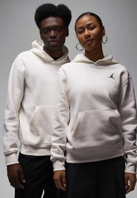 Fehér kapucnis pulóverek elülső zsebbel, fekete Jumpman logóval. Az anyag puha hatású, rugalmas mandzsettákkal és végződésekkel.