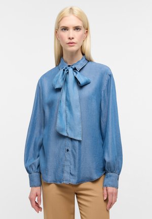Hellblaues Denim-Bluse mit einer Schleifenkragen, langen Ärmeln mit elastischen Manschetten und legerer Passform. Glatte Textur mit Knopfschluss.