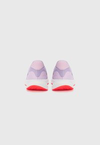Chaussures de sport violettes avec une partie supérieure en mesh texturé, un talon rembourré et une semelle blanche dotée d'un accent rouge sur la bande de roulement.