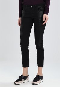 Jean en denim noir avec une coupe slim, taille mi-haute, design à cinq poches et accents texturés subtils sur le tissu.