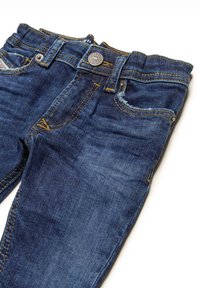 Jeans in denim blu scuro con una vestibilità slim, caratterizzati da cuciture dorate, cinque tasche e un bottone metallico di chiusura in vita.