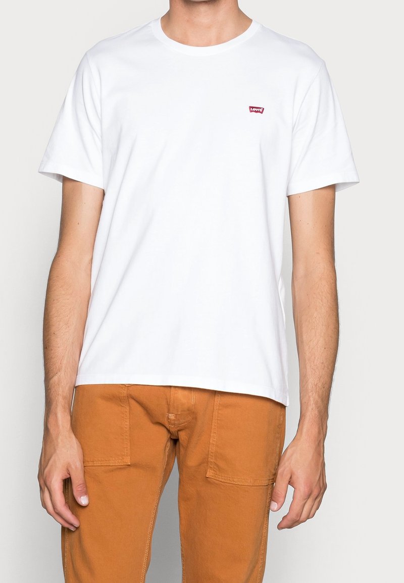 White cotton t-shirt with short sleeves, round neckline, featuring a small red Levi's logo on the left chest.