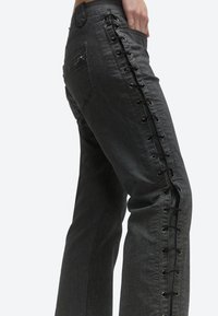 Damskie ciemnoszare dżinsy z czarnym sznurowaniem wzdłuż bocznego szwu od biodra do kostki.