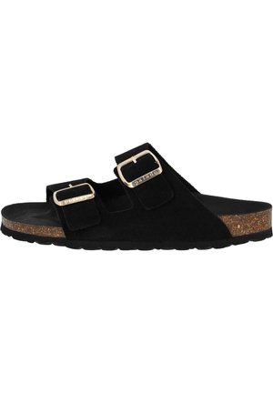 Schwarze Wildleder-Schlipsandalen mit zwei verstellbaren Riemen und metallischen Schnallen, Korkfußbett und Gummisohle. Flaches Design mit minimalen Details.