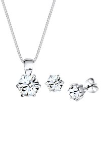 Collana d'argento con pendente rotondo e orecchini a bottone abbinati. Gemme trasparenti e sfaccettate in montature a griffe sicure ne esaltano la lucentezza.