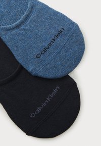 Calvin Klein sinises ja mustades toonides pahklu socksid, millel on sile kudumise tekstuur, tugevdatud konts ja logodetailid kooskõlastatud värvides.