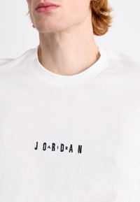 Fehér pamut póló, kontrasztos fekete hímzett "J O R D A N" logóval. Strukturált kerek nyakkivágás, sima textúra és rövid ujjú.