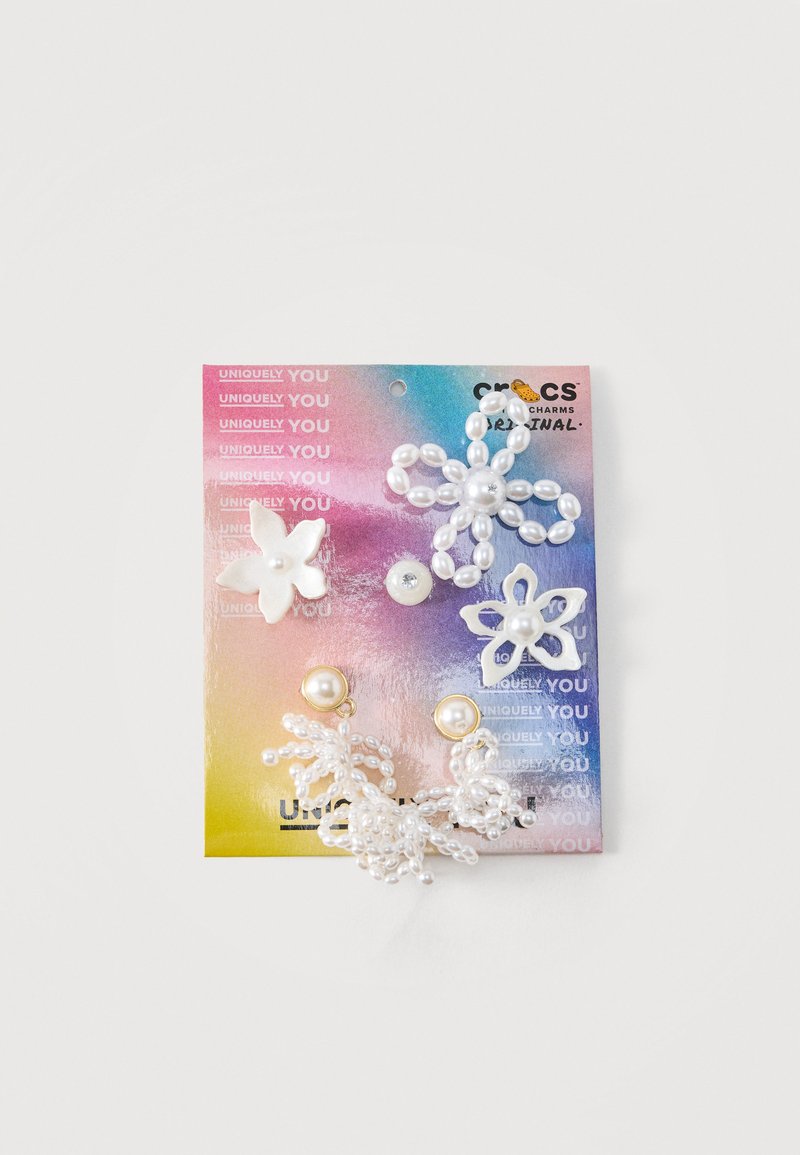 Ensemble de six breloques décoratives en forme de fleurs en perle et résine sur une carte de support dégradée rose, violet et jaune.