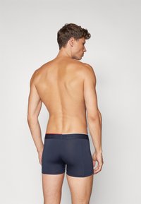 Tumed sinised bokserid venivast kangast, eristuva vöökohtaga, millel on reljeefne kiri "TOMMY HILFIGER".