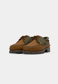 Braune Lederschuhe mit grünen Akzenten, runder Zehenbereich, gestickte Details und Gummisohle mit einem robusten Profil.