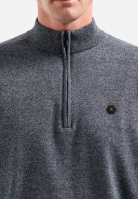 Grijze pullover met ritssluiting, gemaakt van textuurstof. Kenmerken zijn een aansluitende kraag en een klein hexagonaal logoaccent.