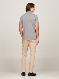 Grå polo-shirt med korte ærmer, stof af bomuld, klassisk krave, parret med beige chinos og sorte loafers, set fra ryggen.
