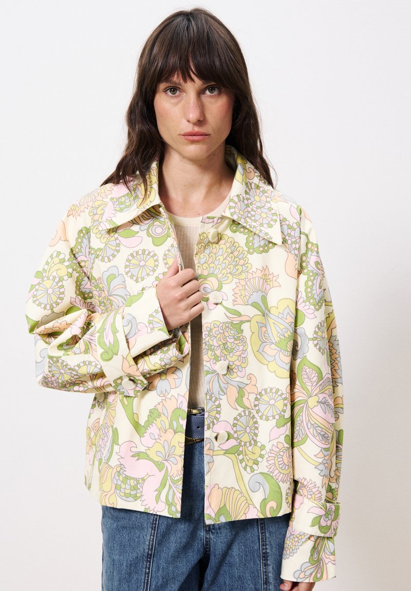 Une veste à motifs floraux dans des couleurs pastel, dotée d'un grand col, de longues manches et d'une fermeture à boutons. Le tissu semble léger.