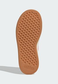 Suela de zapatilla de goma con un patrón texturizado de panal, en color marrón claro y con un logo en relieve. Presenta un diseño de borde suave.