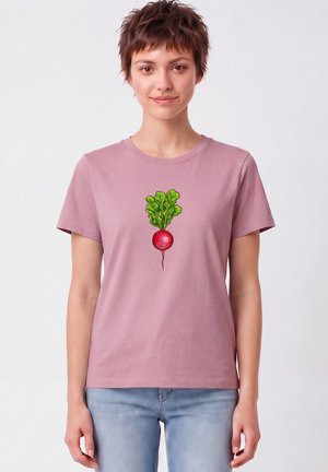 Frau mit kurzen Haaren, die ein hellviolettes T-Shirt trägt, auf dem in der Mitte ein großes Radieschen mit grünen Blättern gedruckt ist.