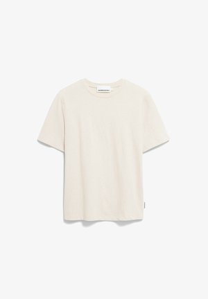 T-shirt à manches courtes de couleur crème, fabriqué en tissu doux, avec un col rond et une petite étiquette logo en bas à gauche.