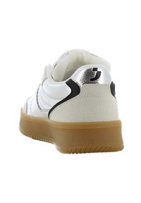 Baskets blanches avec une tige texturée, des accents noirs et un détail de talon en métal argenté. Présente une semelle en caoutchouc gomme et un col rembourré.