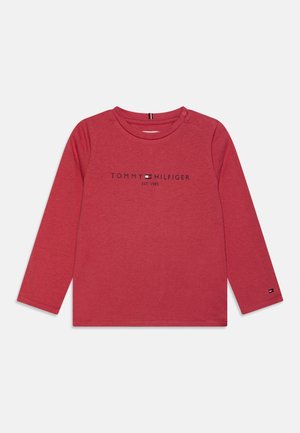 Camiseta roja de manga larga para niño pequeño con logo de Tommy Hilfiger y texto "EST. 1985" en el pecho, cierre con botón en el hombro y pequeño logo en la manga.