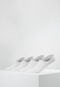 White slip-on socks displayed on a white pedestal. The fabric has a smooth texture with a ribbed pattern along the sides.
