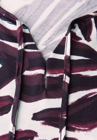 Hoodie met een diepe V-hals en een veelkleurig abstract patroon in bordeauxrood, wit en marineblauw. Zachte stof met zichtbare stiksels.