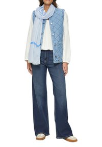 Denimvest met quiltpatroon, witte textuurblouse, wijde, donkere denim jeans en een blauwgestreepte sjaal met logo-detail. Casual schoeisel inbegrepen.