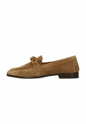 Bruine suède platte loafer met een ronde neus, een decoratieve knoop bovenop en een lage donkerbruine zool.
