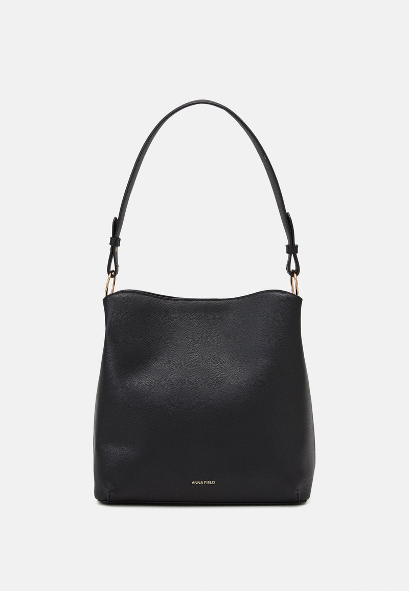 Sac à bandoulière en cuir noir à texture lisse, sommet arrondi et une seule sangle ajustable. Présente un logo de marque doré en bas.