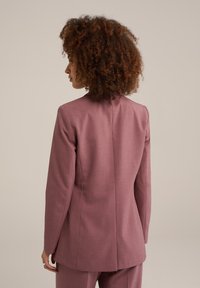 Prisegta švarkas šviesiai mauve spalvos audinyje, turintis struktūruotą siluetą, įpjautas atvartus ir vieną angą gale.