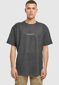 Mørkegrå oversized t-shirt lavet af bomuld, med korte ærmer og rund halsudskæring. Har hvid tekst "METAMORPHOSIS" på brystet.