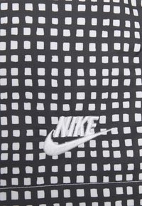 Kšiltovka Nike s černým podkladem a mřížkovým vzorem bílých čtverců, na přední straně vyšívané bílé logo.