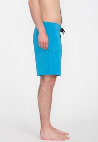 Blaue Schwimmshorts mit einem Kordelzugbund, Seitentasche und einer glatten, leichten Textur. Sichtbare Nähte entlang der Nähte.