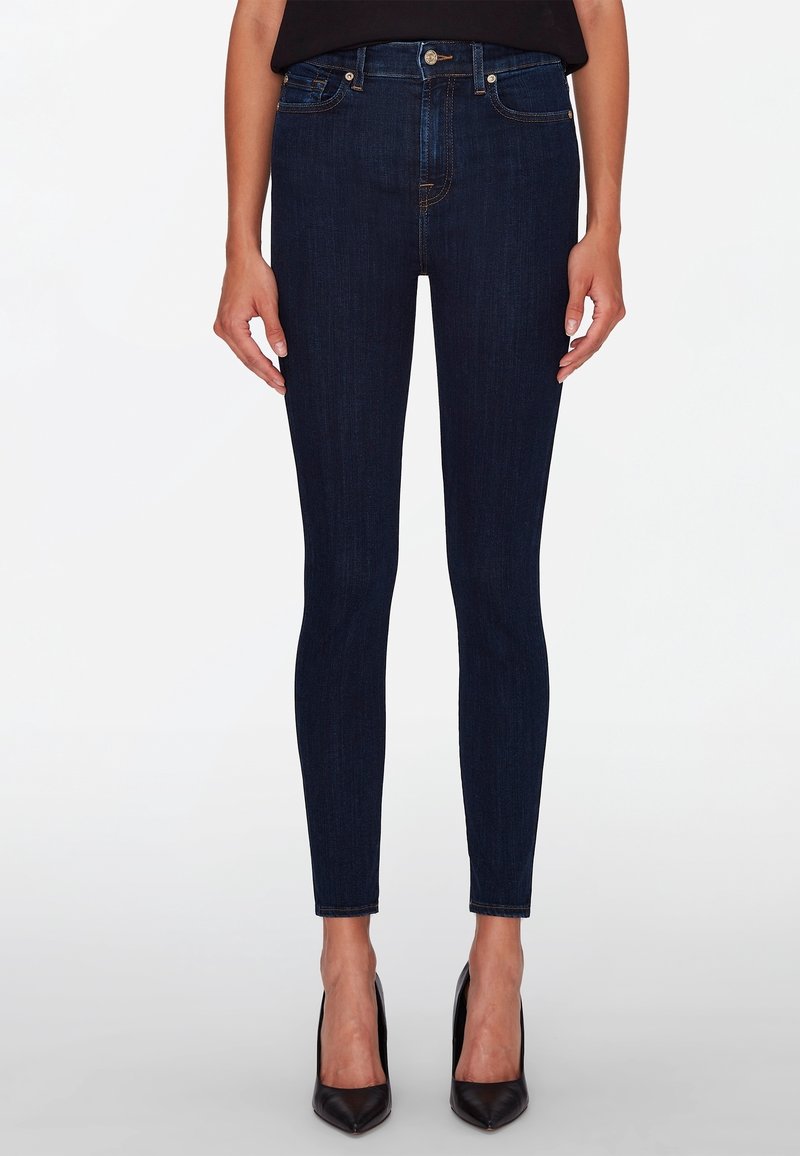 Jeans ajustados de mezclilla azul oscuro con una textura suave. Presentan cinco bolsillos, una cremallera frontal y una silueta entallada.