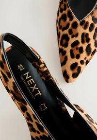 Chaussures à talons hauts en imprimé léopard avec un bout pointu et un design à talon nu. Fabriquées en fourrure douce avec un intérieur noir et un logo doré sur la semelle intérieure.