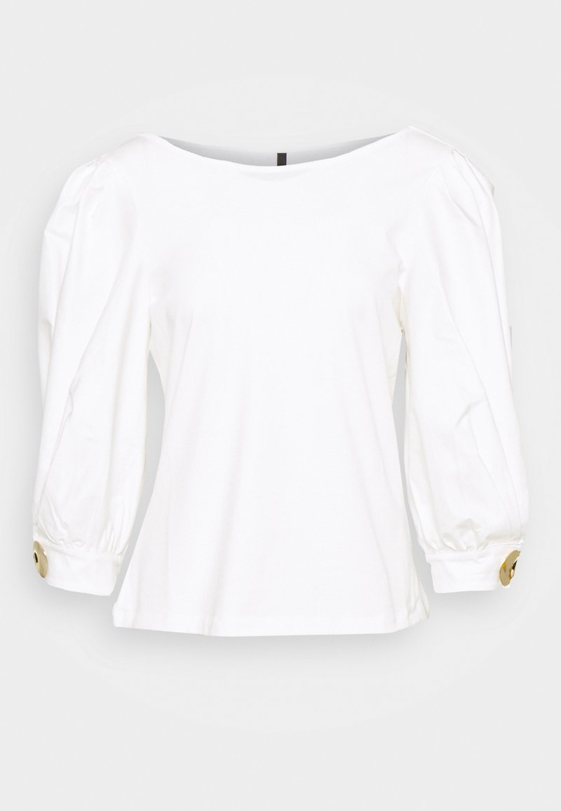 Vit långärmad blus med rundad halsringning, puffärmar och guldbuttonsdetaljer vid ärmsluten. Slät tyg med avslappnad passform.