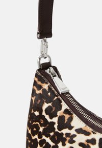 Leopardprint håndtaske med læderrem, sølvhardware og lynlås lukning. Teksturen er blød og pelsagtig.
