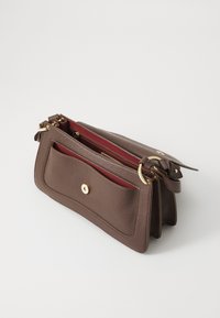 Brown leather handbag with a textured finish, featuring a front pocket, gold hardware, and a red interior. Adjustable strap included.