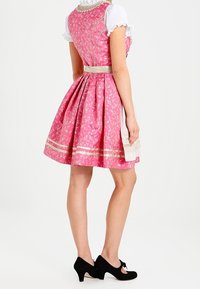 Robe fleurie rose avec un corsage ajusté, une jupe évasée et des accents dorés. Comprend un chemisier blanc en dessous et des talons noirs.