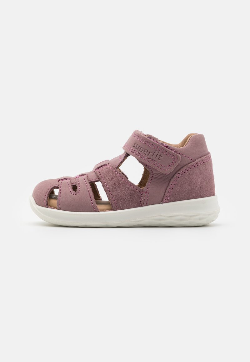 Pink suede sandal featuring a closed toe, multiple cutouts, adjustable Velcro strap, and a white rubber sole for grip and comfort.