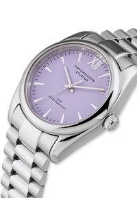 Orologio in acciaio inox argentato con quadrante rotondo di color lilla, indicatori e display per la data. Caratterizzato da un bracciale in metallo a maglie e una corona.