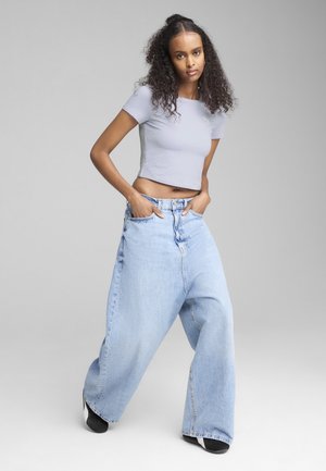 Light gray cropped ribbed top paired with oversized light blue denim jeans, featuring a high-waisted fit and wide legs.