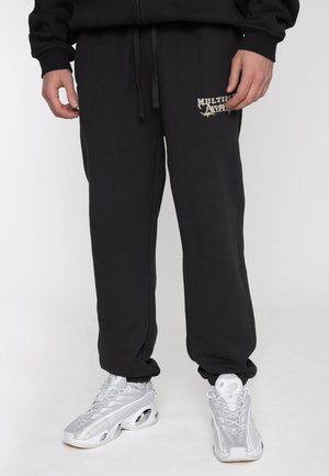 Black sweatpants with drawstring closure, featuring a white printed logo on the left side. Made from soft fabric, with elastic cuffs.