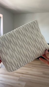 Λευκό τσαντάκι clutch με καπιτονέ σχέδιο, που διαθέτει υφασμάτινη επιφάνεια και στρογγυλεμένες άκρες. Η ραφή αναδεικνύει το σχέδιο και το σχήμα.