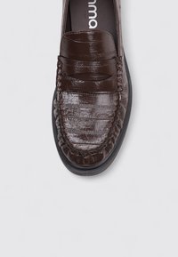 Brown leather loafer with a textured finish, featuring stitched accents and a rubber sole. Design highlights include a pleated vamp.