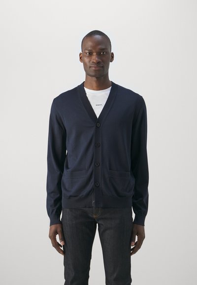 Cárdigan navy con cuello en V, cierre de botones, dos bolsillos frontales, dobladillo y puños acanalados, hecho de un suave material de punto ligero.