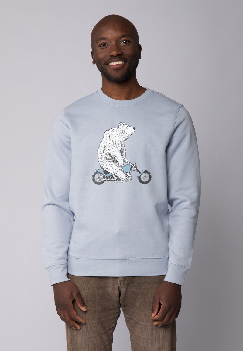 Sweatshirt bleu clair avec un graphique d'un ours blanc montant sur un vélo. Manches et ourlet côtelés avec une texture douce.