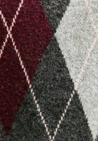 Tissu en mélange de laine avec un motif argyle en bordeaux, gris et gris clair, avec des coutures beiges délimitant les formes de diamant.
