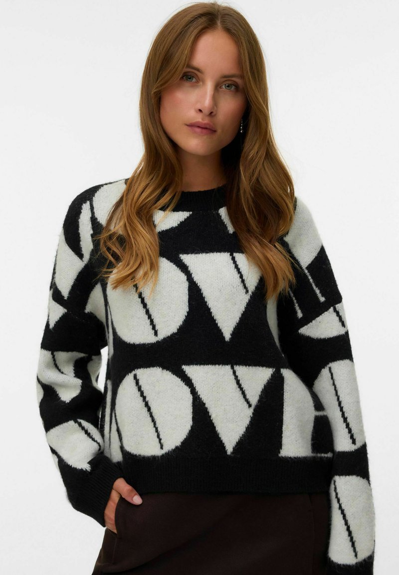 Maglione a maglia bianco e nero con un motivo geometrico caratterizzato da grandi lettere. Texture morbida, scollatura a girocollo e taglio rilassato. Maniche lunghe.